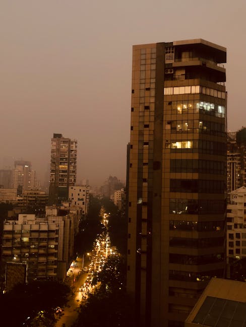 Aerial view of Mumbai's urban skyline at dusk showing lit skyscrapers and bustling streets.